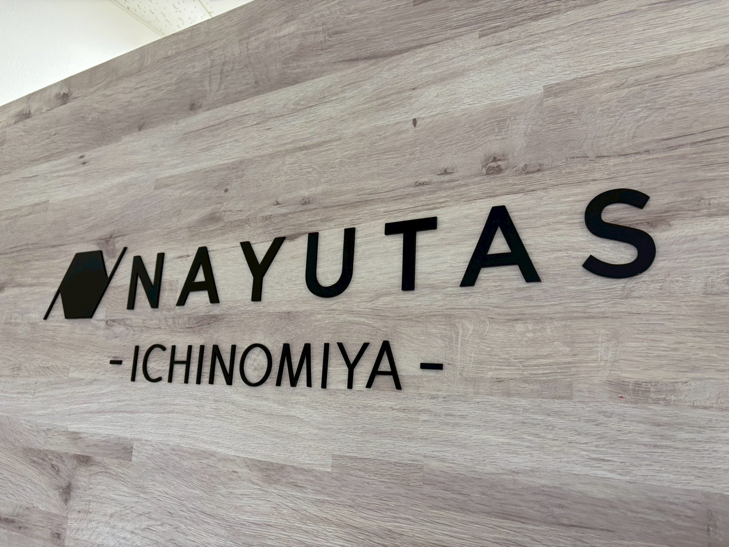 NAYUTAS一宮校の木目壁に設置された校舎ロゴ
